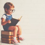 child little girl with glasses reading a books